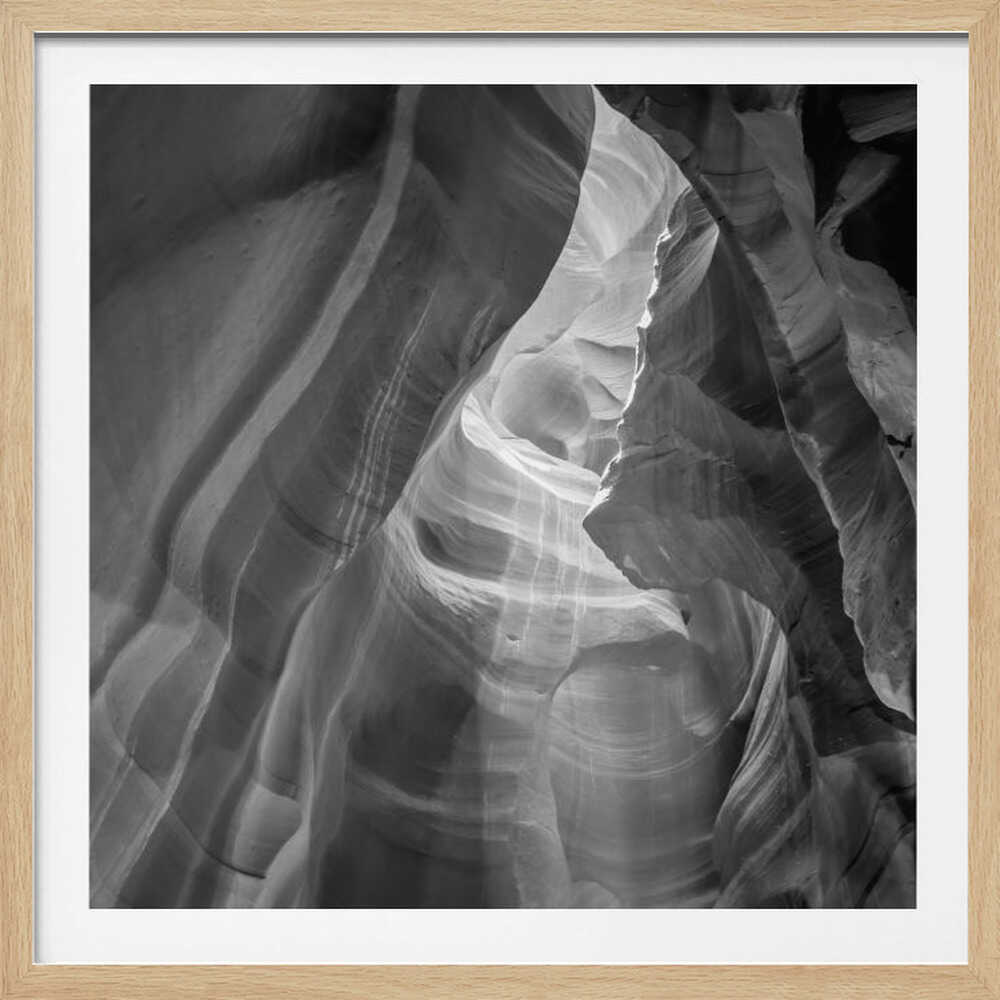 Black and white photo of light in a narrow slot canyon, highlighting smooth, layered rock formations. Nature wall art.