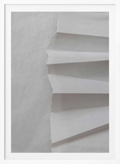 A minimalist composition of folded and torn white paper, showcasing geometric forms and shadows in a black frame.