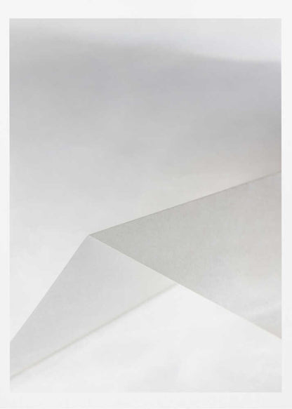 Minimalist abstract art of folded paper creating clean lines and geometric shapes in shades of grey and white.