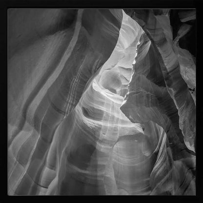 Black and white photo of light in a narrow slot canyon, highlighting smooth, layered rock formations. Nature wall art.