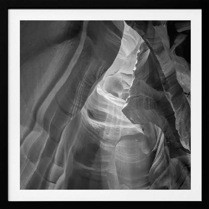 Black and white photo of light in a narrow slot canyon, highlighting smooth, layered rock formations. Nature wall art.