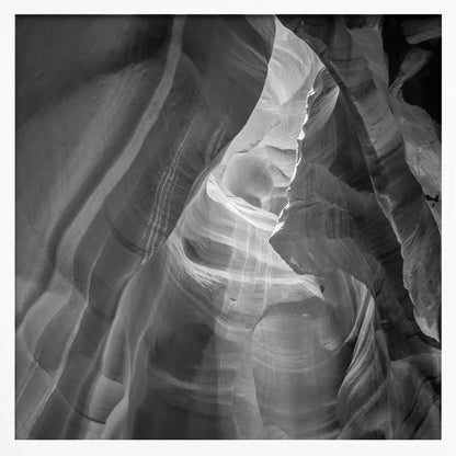 Black and white photo of light in a narrow slot canyon, highlighting smooth, layered rock formations. Nature wall art.