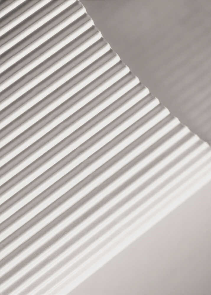 Abstract photograph of a ribbed surface with diagonal lines created by light and shadow, minimalist wall art.