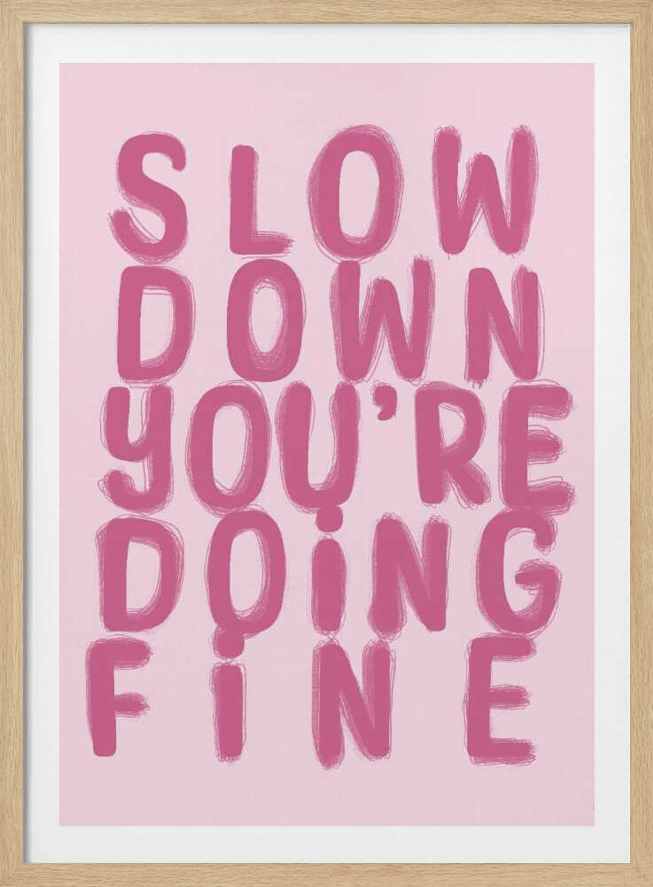 A framed art print featuring the phrase 'SLOW DOWN YOU'RE DOING FINE' in a bold, dark pink, brush-stroke font. The words are stacked vertically against a light pink background, all enclosed within a simple black frame. Artwork