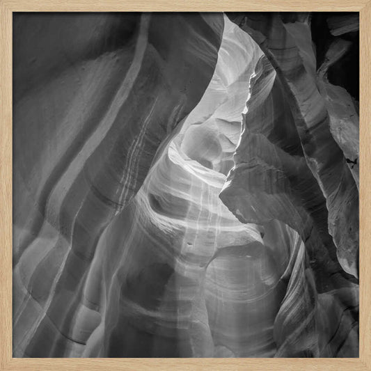 Black and white photo of light in a narrow slot canyon, highlighting smooth, layered rock formations. Nature wall art.