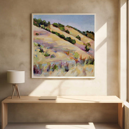An impressionist oil painting of golden, rolling hills dotted with green shrubs under a pale blue sky, framed in light wood.
